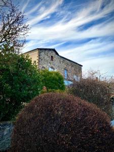 Ermitage Saint Vincent B&B في Vieille-Brioude: مبنى حجري قديم وامامه شجيرات