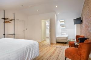 una camera da letto con un letto bianco e una sedia di Our Bird's Nest in the Heart of Antwerp ad Anversa