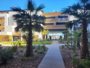 two palm trees in front of a building at Ocean gate in Marseillan