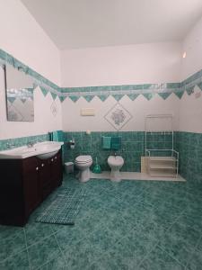 a green and white bathroom with two toilets and a sink at Casa Di Mitri in Carini