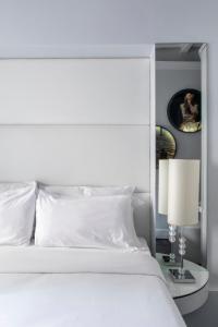 Cama blanca con almohadas blancas y mesa con lámpara en BDB Rooms Margutta, en Roma