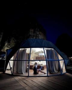 a woman is sitting in a tent in the dark at RUM HiLTON lUXURY CAMP in Wadi Rum