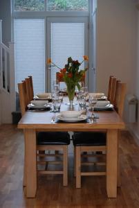 a dining room table with a vase of flowers on it at Valentyne Beach House in Porthtowan