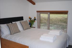 a bedroom with a white bed with towels on it at Valentyne Beach House in Porthtowan