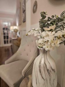 a white vase with flowers on a table with a chair at Antfield house in Inverness