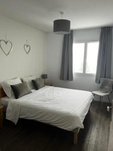een slaapkamer met een groot wit bed met 2 harten aan de muur bij Résidence Les Pleiades - 2 Pièces pour 4 Personnes 93 in Flaine