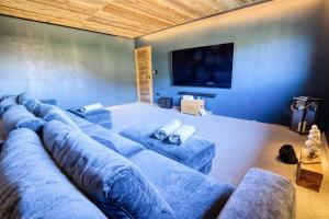 a living room with a large blue couch and a flat screen tv at Chalet - Chalets 101 in Notre-Dame-de-Bellecombe