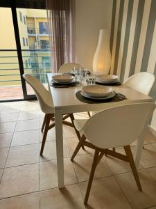 a dining room table with white chairs and a white table and chairsktop at Sunflower Apartment in Armação de Pêra