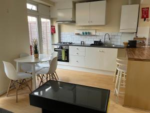 uma cozinha com armários brancos e uma mesa e cadeiras em Sudbury Hill Bedroom with Private Bathroom em Harrow