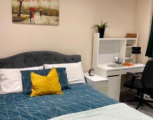 um quarto com uma cama com almofadas amarelas e uma secretária em Sudbury Hill Bedroom with Private Bathroom em Harrow