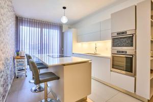 San ĠwannにあるFairways Modern Apartment - Perfect for familiesのカウンターとテーブルと椅子のあるキッチン