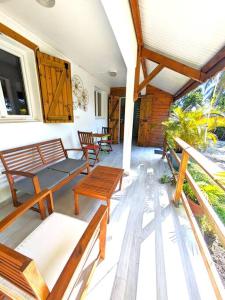 a porch with benches and tables on a house at Appartement - Résidence piscine La Villa Bèl in Sainte-Anne