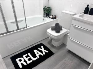 a bathroom with a bath tub and a toilet and a rug at Whole House, FreeParking, Sleeps 5, MK Centre, Work&Leisure in Shenley Brook End