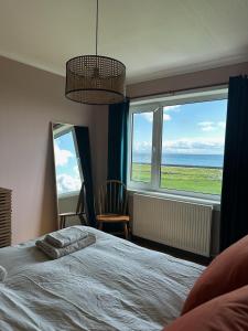 a bedroom with a bed and a view of the ocean at Braighe Cottage in Stornoway
