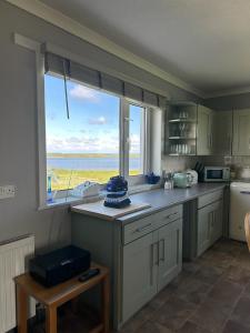 a kitchen with a large window with a view of the ocean at Braighe Cottage in Stornoway