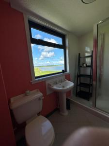 a bathroom with a toilet and a sink and a window at Braighe Cottage in Stornoway
