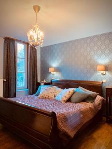 a bedroom with a large bed with a chandelier at Domaine Chateau le Risdoux 20pers, unieke locatie in Vireux-Wallerand