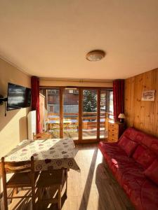 uma sala de estar com um sofá vermelho e uma mesa em Résidence Les Cordeliers - Studio pour 4 Personnes 171 em Valloire