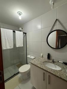 uma casa de banho com um WC, um lavatório e um espelho. em Infinity APT 503 em Maceió
