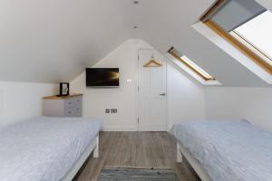 a attic bedroom with two beds and a tv at Modern Seaside House with Hot Tub in Earnley