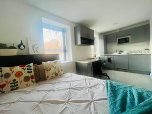 1 Schlafzimmer mit einem großen Bett und einer Küche in der Unterkunft Stretford's Best: Cosy Studio Retreat in Manchester