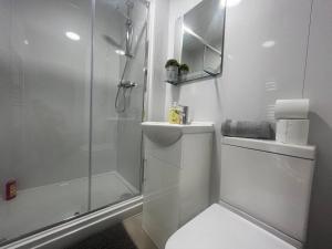 ein weißes Bad mit einer Dusche und einem WC in der Unterkunft Stretford's Best: Cosy Studio Retreat in Manchester