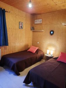 twee bedden in een kamer met houten wanden bij Normandie chalet N70 piscine lac golf in Saint-Manvieu-Bocage