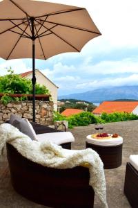 a patio with chairs and an umbrella and a table at Apartmani Bire in Lumbarda
