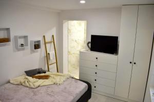 a bedroom with a tv and a dresser with a bed at Apartmani Bire in Lumbarda