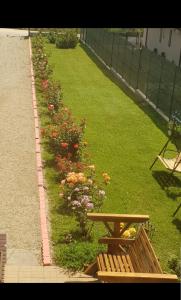 un jardin avec un banc en bois et des fleurs dans l'établissement Casa Rustica, à Mamaia Nord – Năvodari