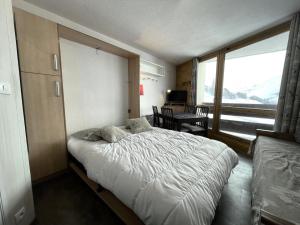 a bedroom with a bed and a large window at Résidence Grande Masse - Studio pour 3 Personnes 911 in Les Menuires