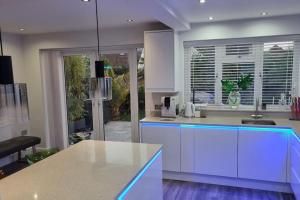 uma cozinha com armários brancos e uma ilha azul em Northbourne House em Longham