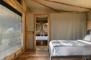a bedroom with a bed and two mirrors at Anantya Serengeti in Serengeti