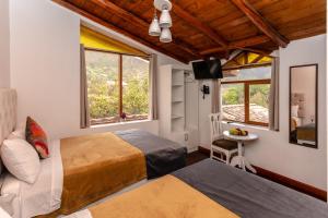 a bedroom with two beds and a tv and a window at Indavesa Valle Sagrado Collection in Calca