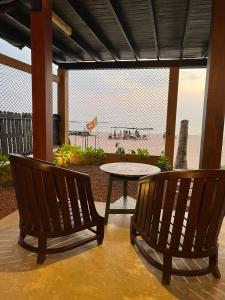 2 bancs et une table en face d'une plage dans l'établissement The Oceanfront Residence, à Ambalangoda