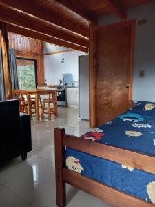 Cet appartement comprend une chambre avec un lit et une cuisine avec une table. dans l'établissement Cabaña 2 Vive Villarrica, à Villarrica