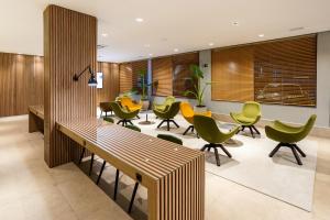 a lobby with green chairs and a long table at Momax Hotel in Marília