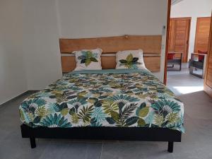 Una cama con un edredón y almohadas de colores en Lodge belle nature, piscine privée, grand jardin, 900 m de la plage de grande anse, en Deshaies