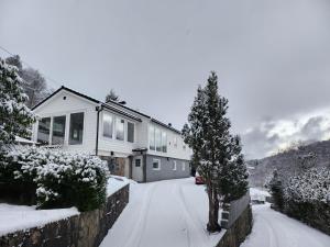 Fjordclaw SNM- adjoining the Bergen city & Nature في بيرغِن: منزل مغطى بالثلج مع شجرة