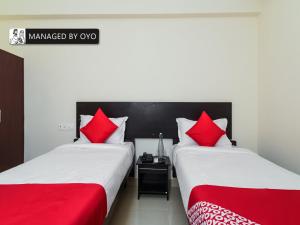 two beds with red pillows in a room at Super Collection O Jagadamba Near Beach Road in Visakhapatnam
