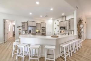 a kitchen with a white counter and white stools at 5BR Lux Home w Pool, Hot Tub, Waterfall,RV parking in Las Vegas