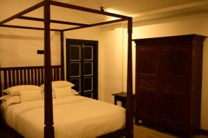 - une chambre avec un lit à baldaquin et une armoire en bois dans l'établissement The Oceanfront Residence, à Ambalangoda