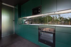 a green kitchen with a stove and a microwave at Unique Modern Cabin with Views 