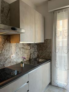 una cocina con armarios blancos y fregadero en Orchidea Home, en Rávena