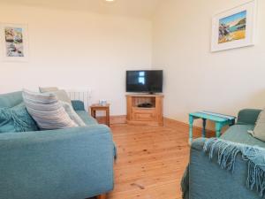 a living room with two blue couches and a tv at Kerensa ha-Kres in Sennen