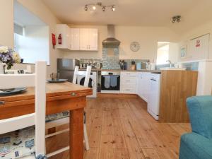 a kitchen with white cabinets and a wooden table at Kerensa ha-Kres in Sennen