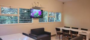 Habitación con mesa y TV en la pared. en Casa El Sosiego, Reserva Forestal en Mar del Plata