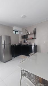 a kitchen with a stainless steel refrigerator and a table at Casa mobiliada de 2 suítes na R São Lázaro 2367 - 2370 - Jardim Gonzaga in Juazeiro do Norte