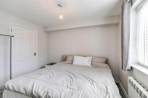 a white bedroom with a bed with a window at Welwyn Garden City Long stay flat in Welwyn Garden City