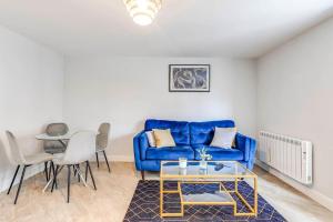 a living room with a blue couch and a table at Welwyn Garden City Long stay flat in Welwyn Garden City